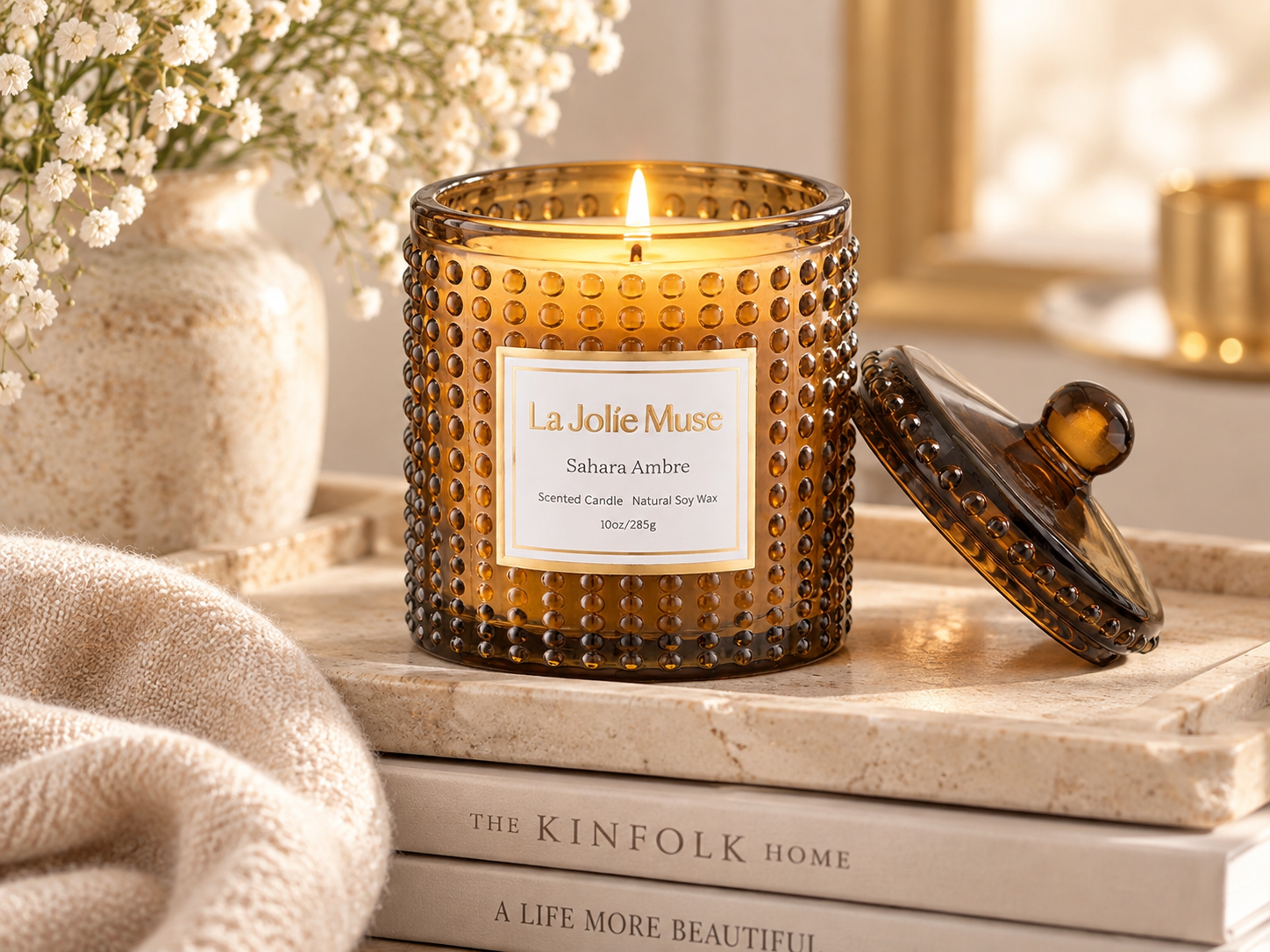 Amber glass candle with lid styled on a tabletop with neutral decor for a warm and elegant home fragrance scene.